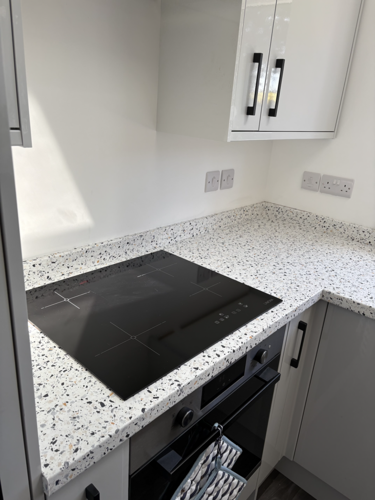 Speckled wrapped kitchen worktop beside a black hob in Bawburgh