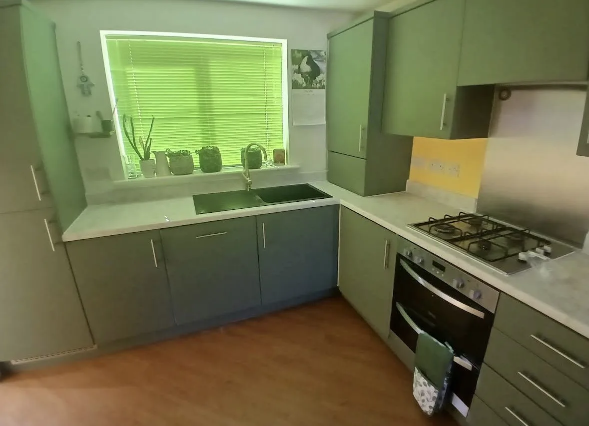 Completed sage green kitchen wrap in Dereham with white marble-effect worktops and fitted sink