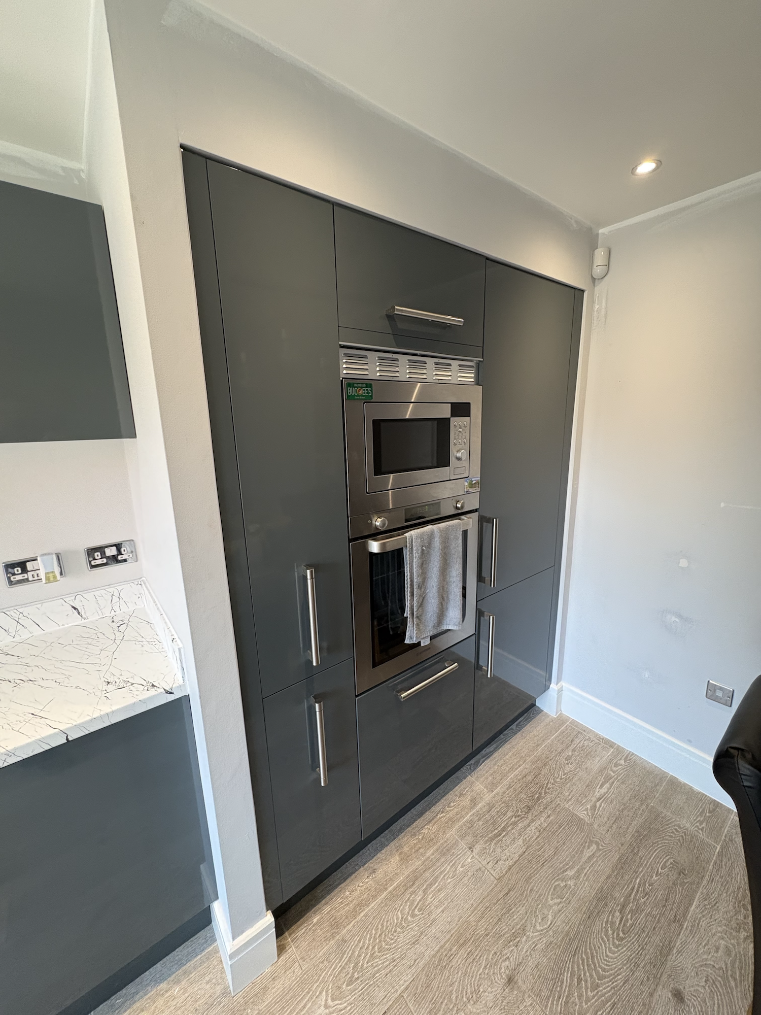 Gloss grey wrapped kitchen cupboards and white marble-effect worktop in Swaffham